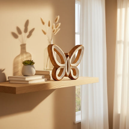 DekoSturm natural mango wood butterfly decoration with white inlay, 15x13x2cm, on a shelf with books and a plant.